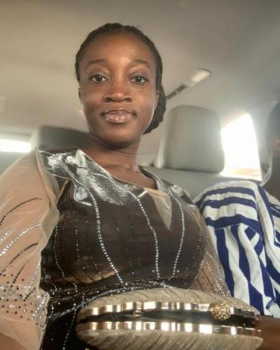 A woman holds a clutch purse while sitting in a car.