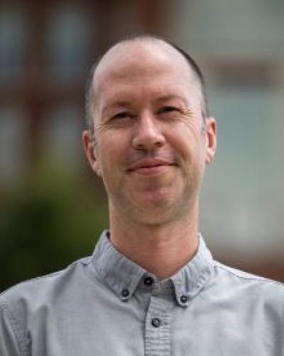 A man smiles while looking at the camera.